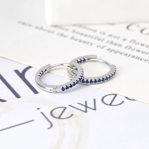 Macro shot of S925 silver huggie earrings with pavé-set deep blue zircon stones