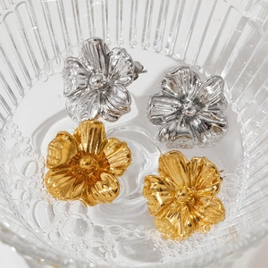 Gros plan artistique de boucles d'oreilles fleurs dorées et argentées dans l'eau