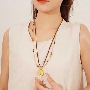 Close-up of double-layer leather necklace with golden heart lock and beaded key pendant