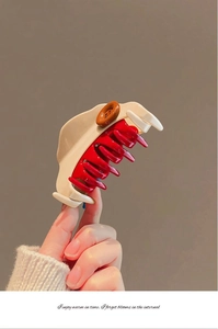 Gros plan sur une pince à cheveux rétro en résine crème et rouge avec bouton