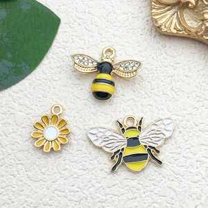 Detailed view of DIY bee and daisy charms with colorful enamel on golden alloy base