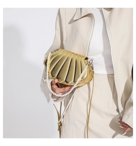 Details der goldenen Muschel-Handtasche mit Kunstperlengriff und strukturierter Oberfläche