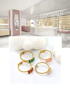 Detailed view of four golden twisted rope rings featuring emerald, pink, and red gemstones