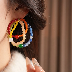 Detail of bohemian multilayered colorful bead hoop earrings on a female model