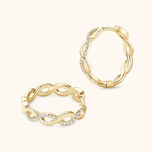 Close-up of golden twisted rope earrings with sparkling zircon stones inlay detail