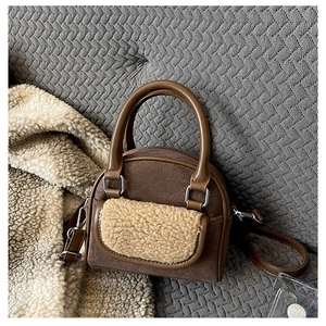 Detailed view of dark brown suede texture and beige faux shearling pocket on stylish bag