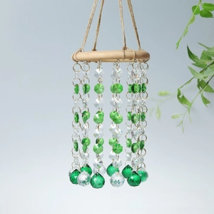 Close-up of green crystal beads and faceted glass ball hanging on a natural wooden ring