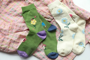 Detailed view of cotton blend socks with forest fairy motifs on pink checkered cloth