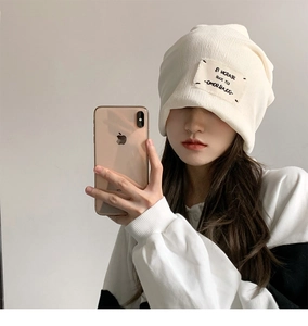 Detailed macro view of cream white ribbed knit beanie with stylish embroidered patch