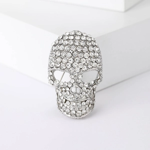Sparkling silver skull brooch with rhinestones on a minimalist white background