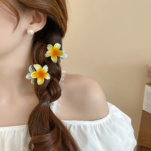 Detail showing colorful gradient sunflower hair claws worn by a model in a cozy setting