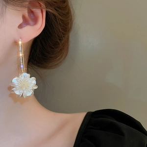 Gros plan de boucles d'oreilles fleurs blanches et strass sur un modèle élégant