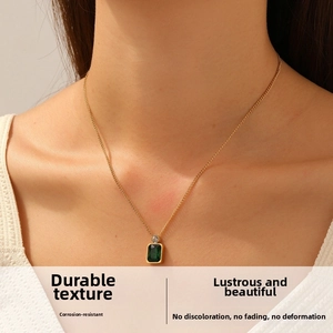 Macro detail of gold-plated pendant with green rectangular gem and sparkling diamond accent