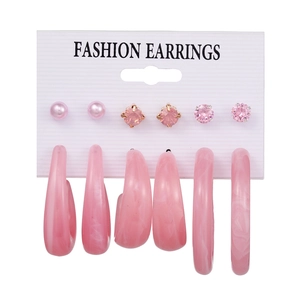 Detail of pink earring set with faux pearls, crystals, and hoop designs on display card