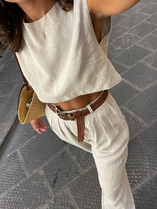 Detailstruktur des beigen ärmellosen Leinentops und der weiten Hose mit Flechtgürtel
