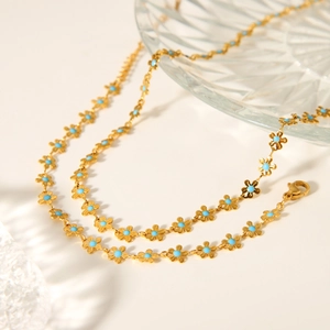 Macro view of gold stainless steel flower necklace with light blue enamel and lobster clasp