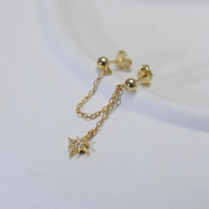 Detailed view of golden chain earrings with star pendant and sparkling white zircon stones