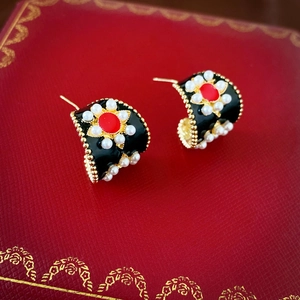 Vue macro de boucles d'oreilles vintage avec motifs floraux rouge et noir et perles