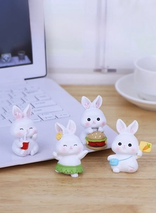 Set of four cute miniature resin rabbit figurines displayed on a cozy office desk