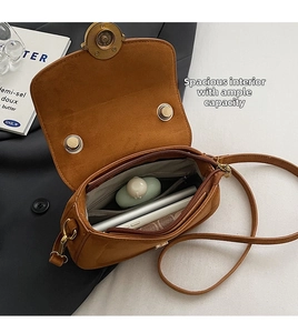 Detail of the large internal capacity and zipper pocket of this brown suede saddle bag