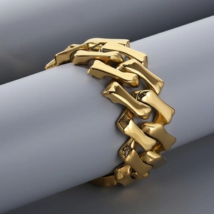 Gold stainless steel Cuban link bracelet displayed on a professional cylinder prop