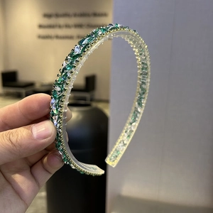 Close-up of green crystal rhinestones on a silver baroque headband accessory