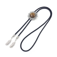 Detail of silver sunburst bolo tie slide with brown gemstone and metal feather charms