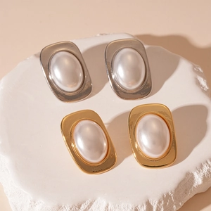 Elegant gold and silver geometric earrings with large oval pearls on stone stand