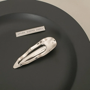 Detail of silver wavy metal hair clip on black plate with sleek polished finish
