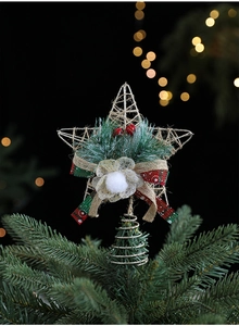 Detail of a golden wire star Christmas tree topper with pine needles and red berries