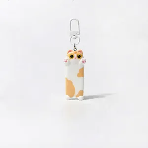 Close-up of handmade cartoon cat keychain with white plastic hook and orange spots