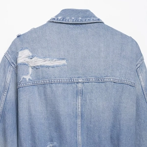 Back view of light blue denim jacket with distressed ripped details and premium stitching