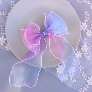 Detail view of large gradient pink and blue sheer bow hair clip on a ceramic tray