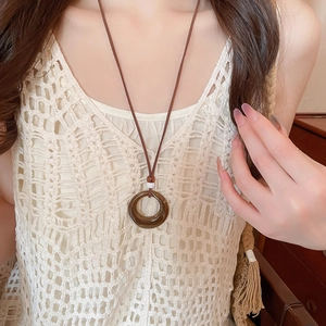 Detailed view of the dark brown resin circle pendant on a brown woven cord necklace