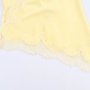 Close-up of yellow satin fabric with delicate off-white eyelash lace trim detailing