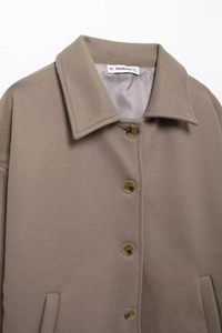 Close-up of the BBWMWOMAN brand collar label and detailed wool blend fabric texture