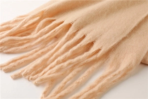 Détail de la texture douce de l'écharpe en mohair avec de longues franges beige