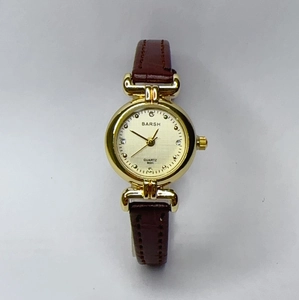 Detail of quartz watch with gold round case, champagne dial and brown leather strap