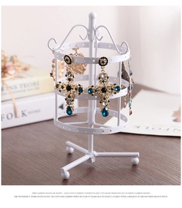 Close-up of white rotating metal earring stand with three tiers and stable tripod base