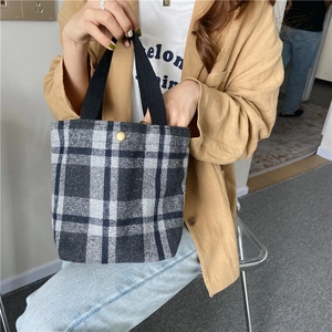 Professional model holding a stylish grey plaid wool lunch bag with minimalist design
