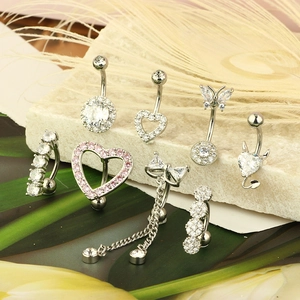 Various stainless steel belly rings with zircon stones on natural stone with leaves