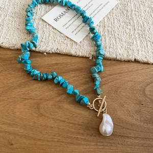 Detail of turquoise beaded necklace with baroque pearl pendant and golden toggle clasp