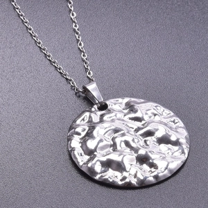 Detailed close-up of a silver stainless steel round pendant with irregular hammered texture