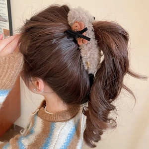 Detail of plush bear hair claw with khaki fleece and black velvet bow on a model