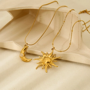 Gold-plated stainless steel necklaces with moon and sun charms on elegant white sculpture