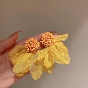 Detailed close-up of yellow and orange organza flower earrings with handcrafted bead clusters