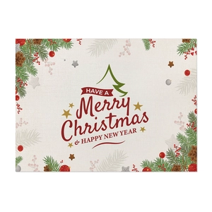 Detail of Christmas placemat with green botanical print and holiday text on linen fabric