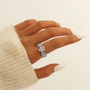 Detail shot of colorful enamel daisy ring on hand with pink and blue floral accents