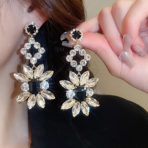 Détail de boucles d'oreilles fleur irrégulières de luxe avec cristaux noirs et clairs