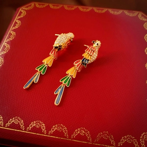 Close-up of gold-plated parrot tassel earrings with colorful enamel on a luxury jewelry box